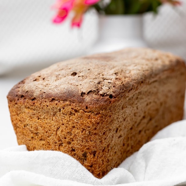 fresh khorasan wheat bread on a white tablecloth with flowers in the background made using Campbell Farm Grains