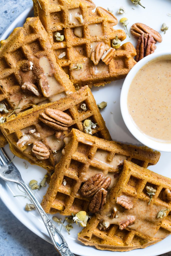 closeup of whole grain khorasan wheat sourdough waffle with pecans and butter syrup on a plate with a fork